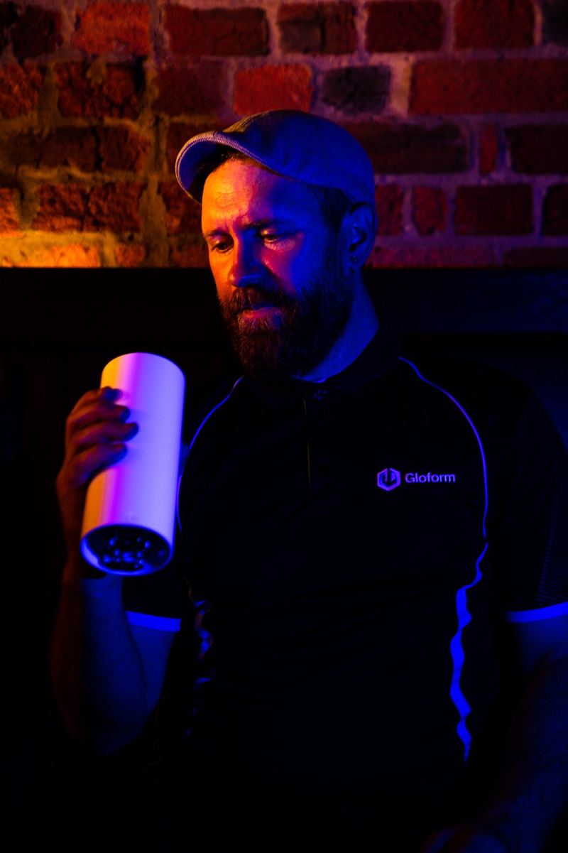 Blake holding a lit cylinder fitting against a brick wall
