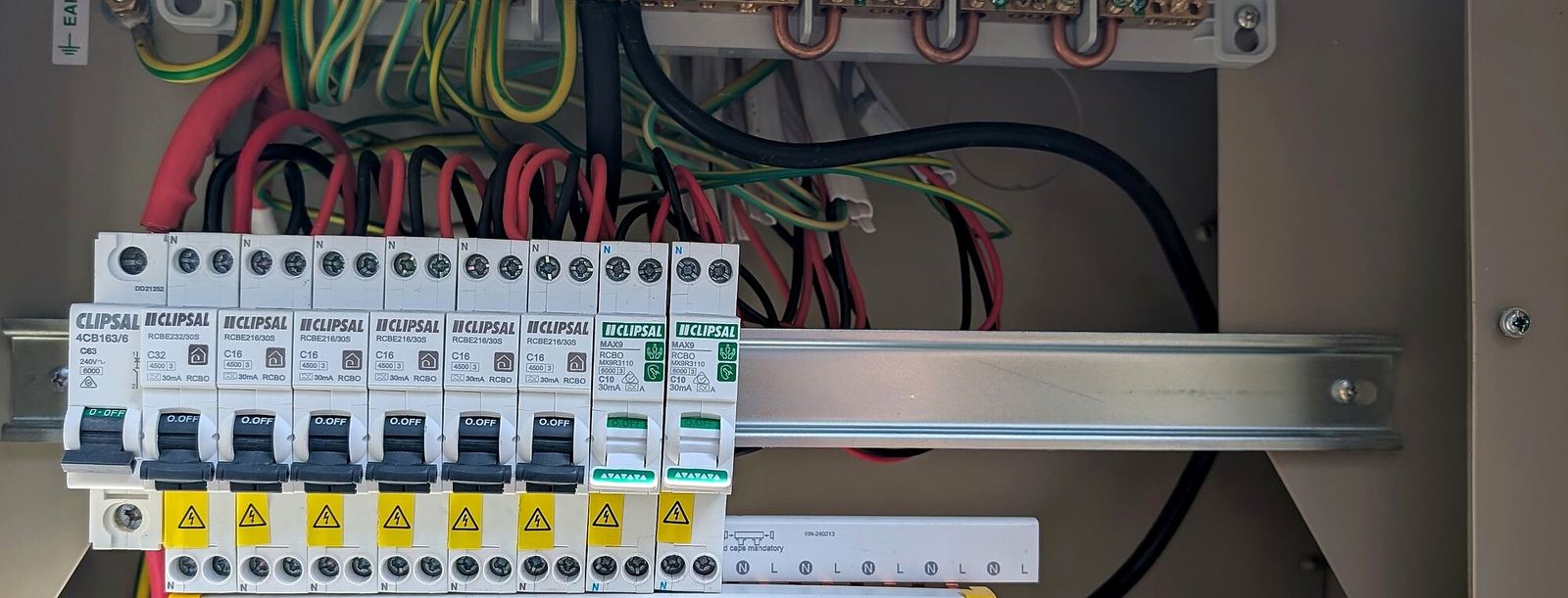Open switchboard with circuit breakers and labelled earth wiring