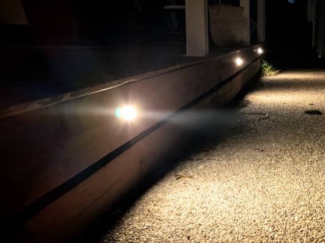 Small recessed lights set into a timber deck edge, lighting a gravel driveway at night in Mornington