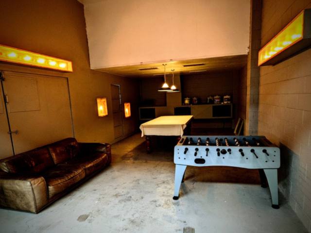 Games room with a leather couch, a foosball table, warm wall lights, and pendants over a table in Mornington
