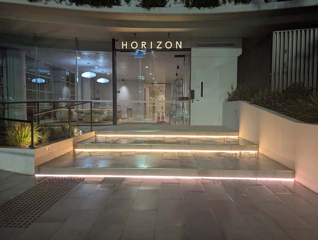 Horizon Building entrance in Frankston at night, with the HORIZON sign lit above glass doors and LED strip lights under each step