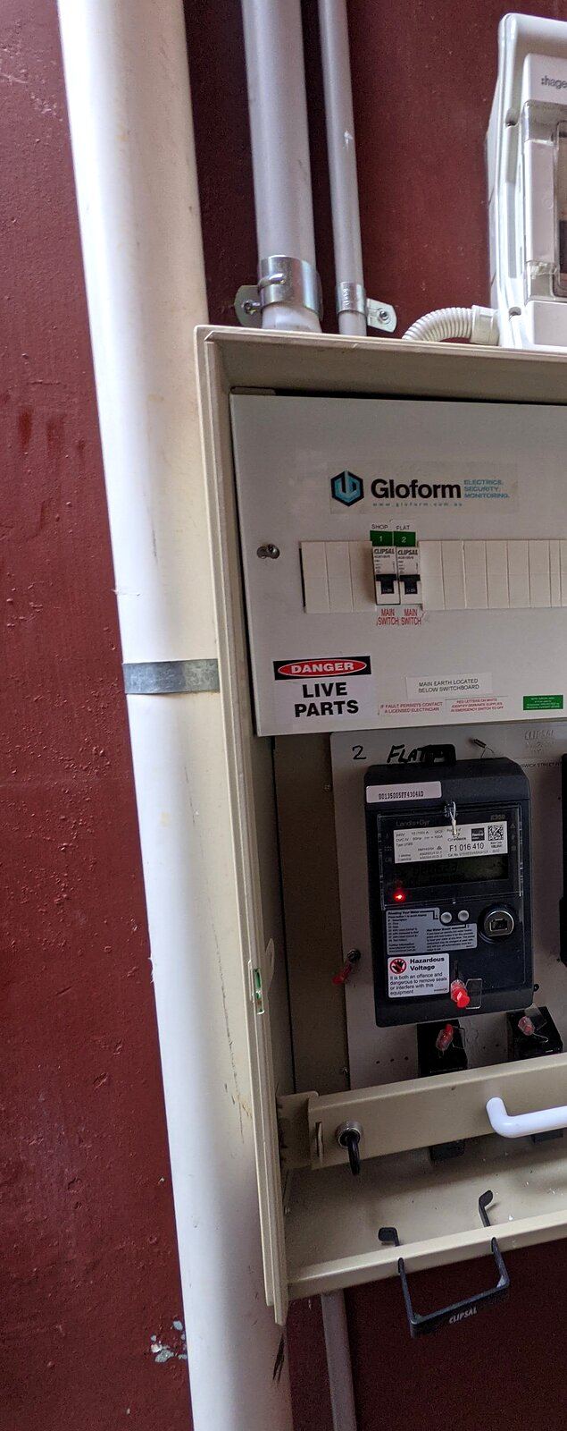 Open meter box with labelled main switches and a digital meter