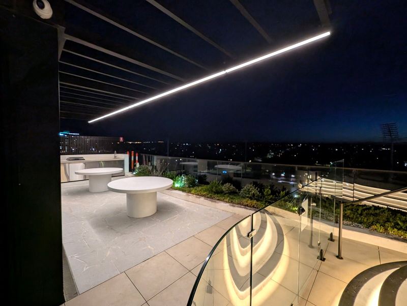 Linear LED light under a rooftop pergola at night