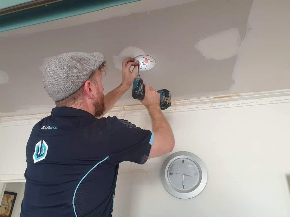 Smoke alarm being fitted to a ceiling